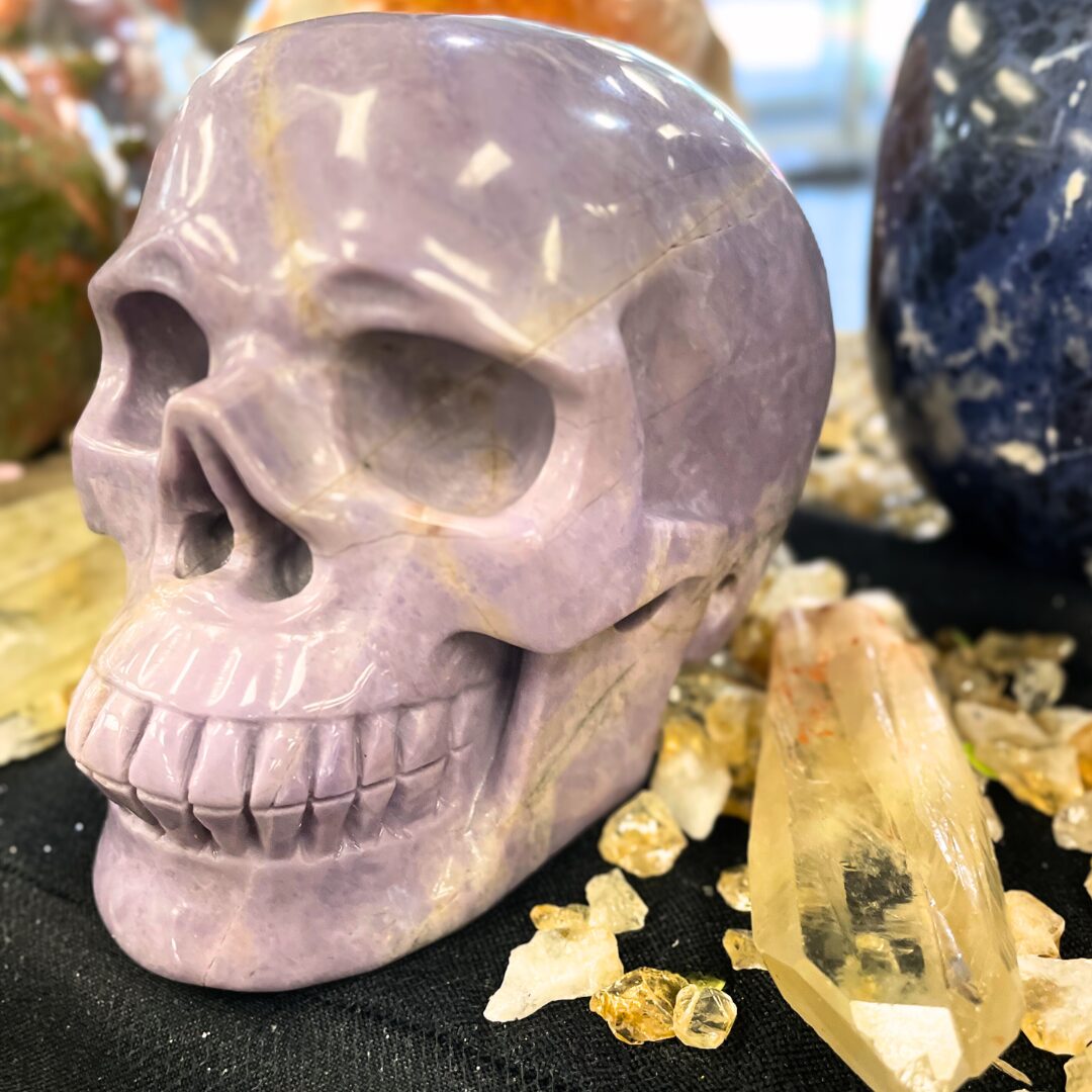 Purple jadeite skull with citrine pieces next to it.